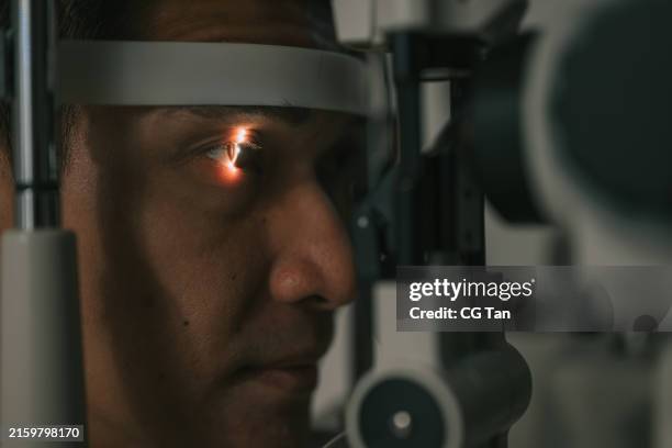 asian chinese man doing eye test retina scan checking eyesight in ophthalmological clinic - cornea stock pictures, royalty-free photos & images