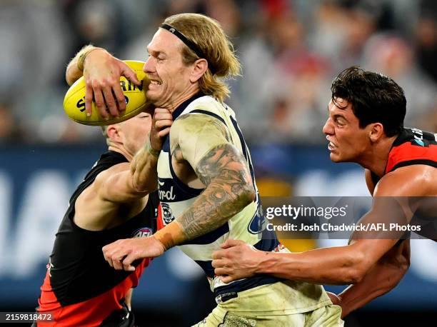 Tom Stewart of the Cats is tackled by Archie Perkins of the Bombers during the round 16 AFL match between Geelong Cats and Essendon Bombers at...