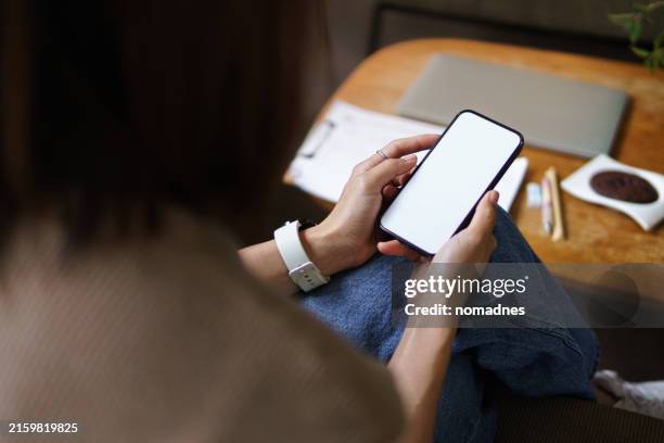 woman in casual clothing using smartphone with blank screen for mobile app display. over shoulder view. - over the shoulder view stock pictures, royalty-free photos & images