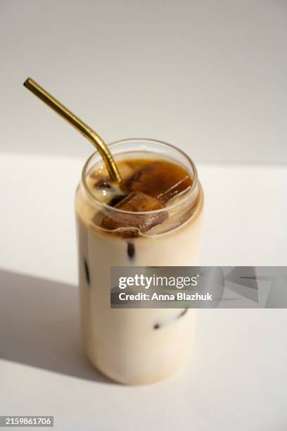 glass of cold coffee drink, iced latte against white background in bright sunlight - iced coffee stock pictures, royalty-free photos & images