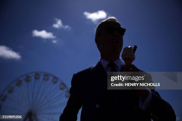 Reform UK leader Nigel Farage is silhouetted as he eats a 99 Flake ice cream in Clacton-on-Sea, eastern England, on July 4, 2024 as Britain holds a...
