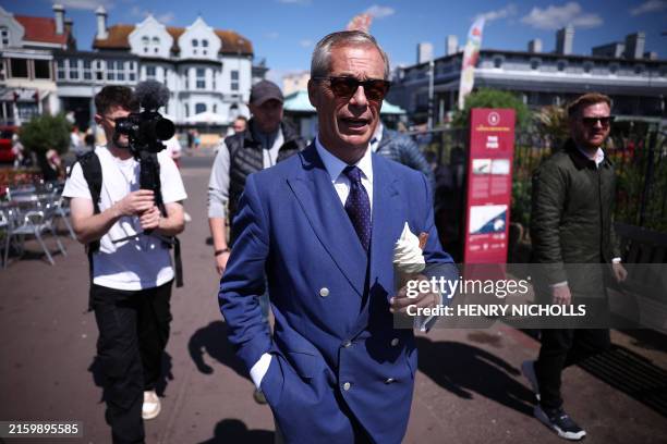 Reform UK leader Nigel Farage eats a 99 Flake ice cream while walking in Clacton-on-Sea, eastern England, on July 4, 2024 as Britain holds a general...
