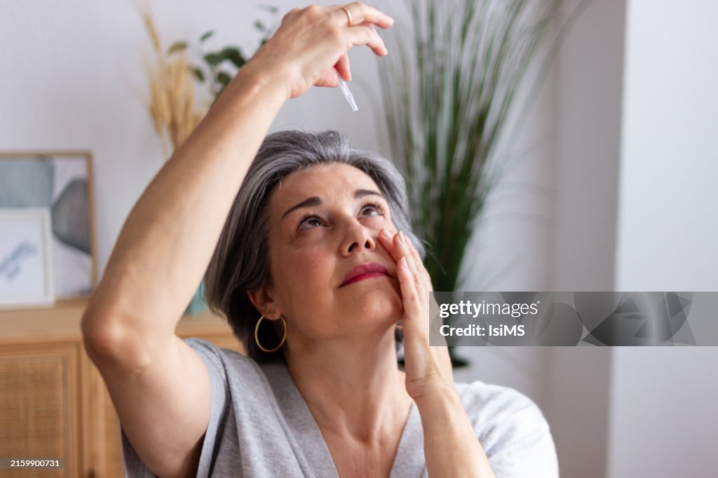 Senior woman applying eye drops suffering from cataract and glaucoma