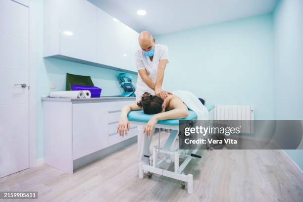 panoramic view of physical therapist working with patient at stretcher - banc de massage photos et images de collection