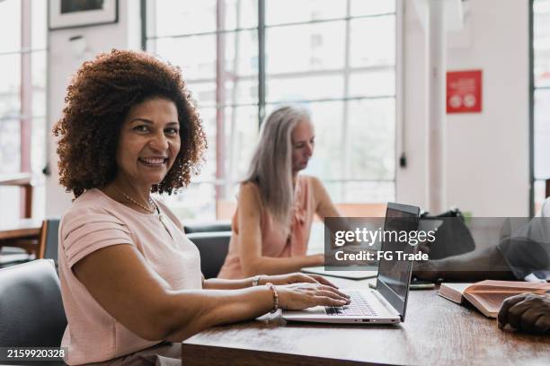 retrato de una mujer madura usando una computadora portátil durante una reunión en la oficina - espacio de trabajo virtual compartido fotografías e imágenes de stock