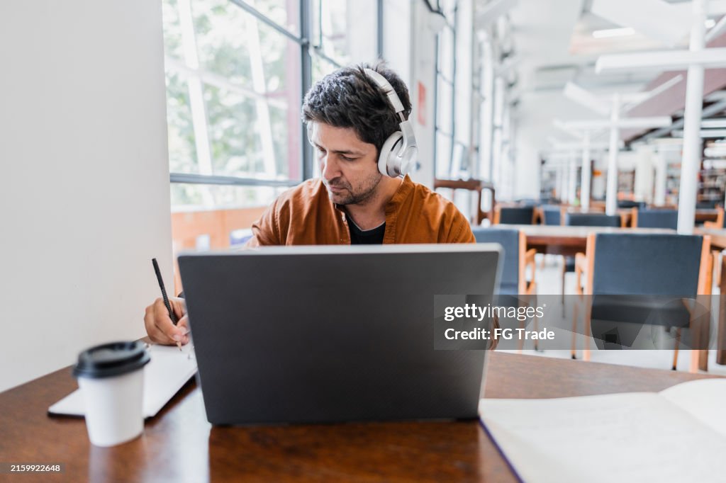 Mid adult man working using laptop at library