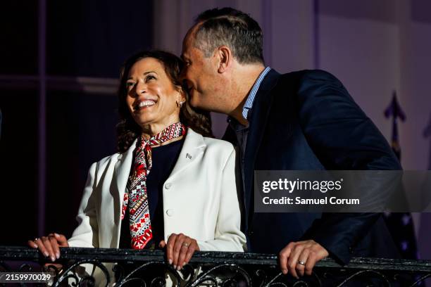 Second Gentleman Doug Emhoff whispers to Vice President Kamala Harris as they watch the fireworks over the National Mall from the White House balcony...