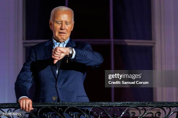 President Joe Biden checks his watch as he steps out onto the balcony of the White House to view the fireworks over the National Mall during a 4th of...