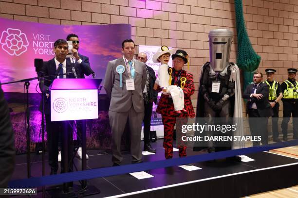 Independent candidate Niko Omilana holds an "L" behind Britain's Prime Minister and Conservative Party leader Rishi Sunak as he delivers a speech...