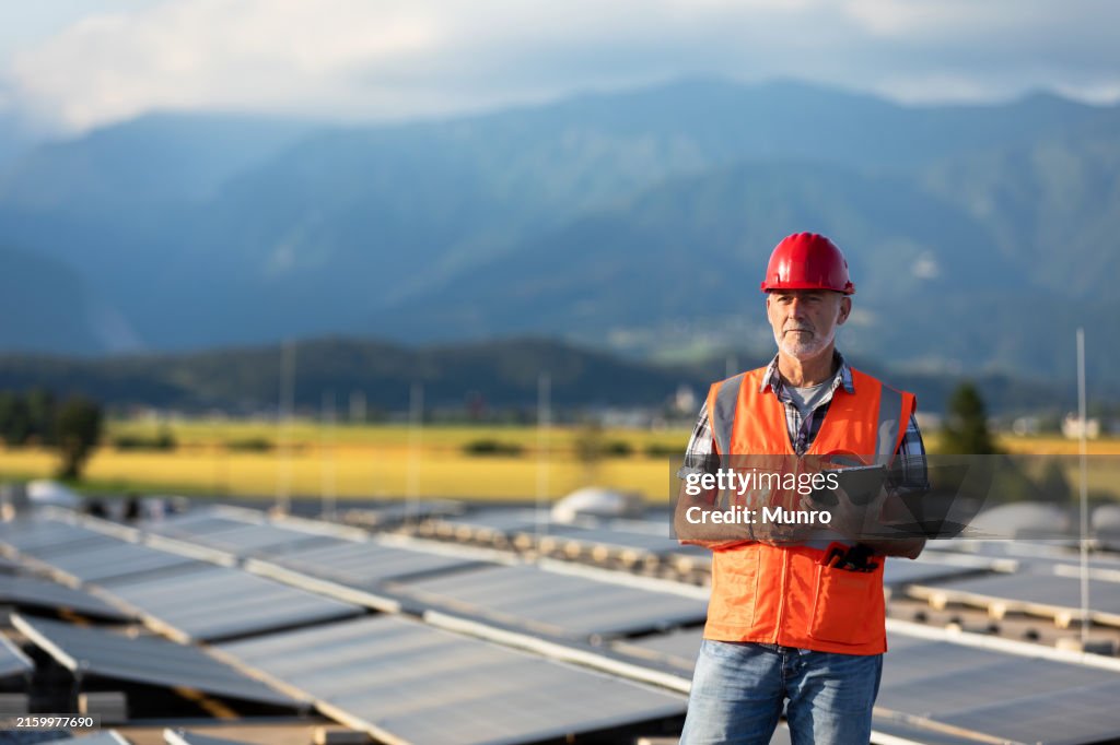 Technician using tablet and checking solar power plant installed on building roof