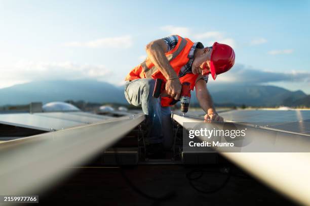 técnico instalando panel solar en el tejado de un edificio - albañil fotografías e imágenes de stock