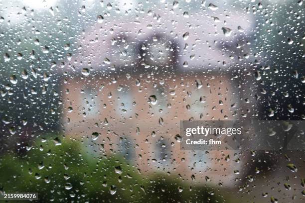 raindrops on a window with a residential building in the background - rainy day window stock pictures, royalty-free photos & images
