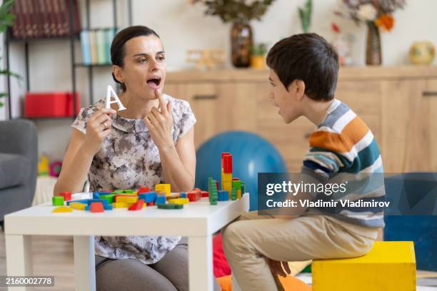 teacher using sign language with young boy - autism stock pictures, royalty-free photos & images