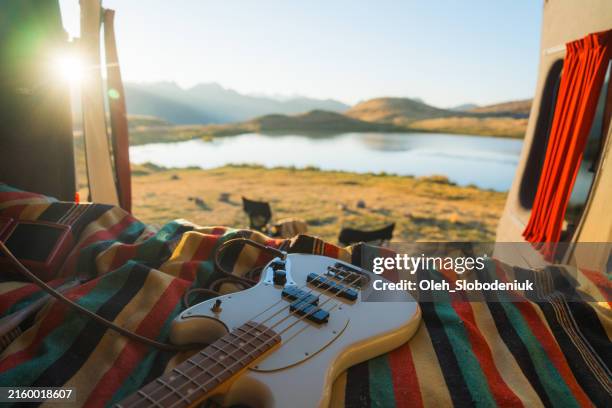 electric bass guitar laying on bed in camper van - bass guitar stock pictures, royalty-free photos & images