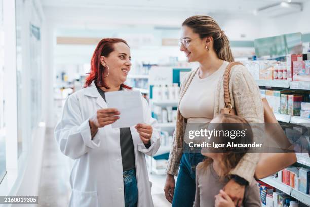 farmacéutica asiste a una madre con su hija - farmacia fotografías e imágenes de stock