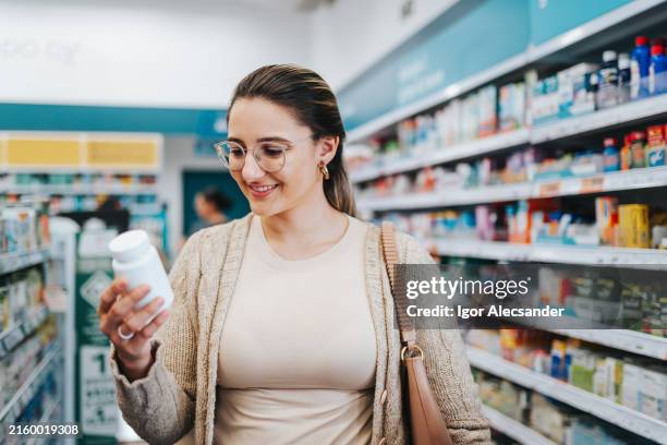woman choosing supplements at the pharmacy - chemist stock pictures, royalty-free photos & images
