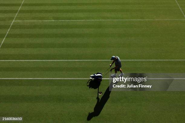 Member of the ground staff is seen painting lines ahead of play during day one of The Championships Wimbledon 2024 at All England Lawn Tennis and...