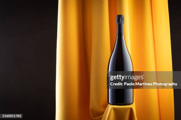 champagne bottle against yellow fabric - sektkorken stock-fotos und bilder