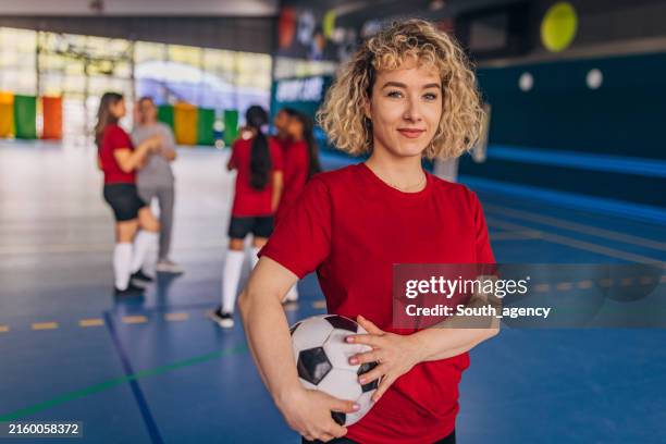 girl with curly hair in red shirt holding soccer ball - futebol de salão imagens e fotografias de stock