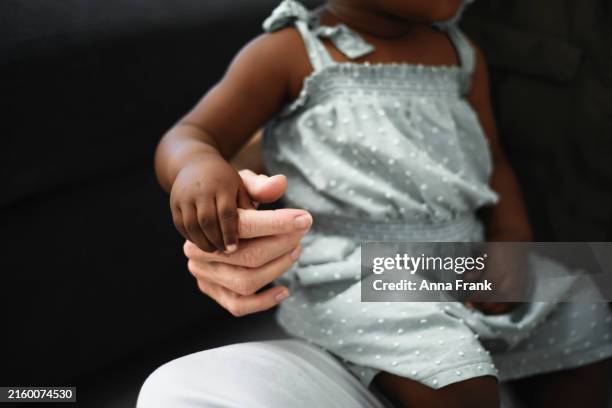 eine mutter oder großmutter sitzt mit ihrem adoptivkind im wohnzimmer - adoption stock-fotos und bilder