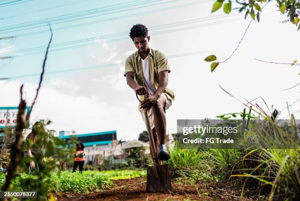 young man working with a shovel on a community garden - digging stock pictures, royalty-free photos & images