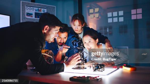 la reunión de ingenieros del equipo y el análisis están llevando a cabo un experimento con robots para el desarrollo futuro de robots. - inventor fotografías e imágenes de stock