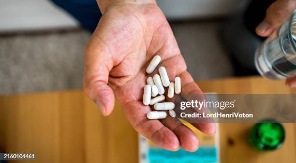 l'uomo anziano prende le pillole con un bicchiere d'acqua - prendere-le-pillole foto e immagini stock