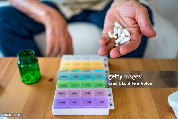 senior man organizes prescription drug tablets - daily pill pack stock pictures, royalty-free photos & images