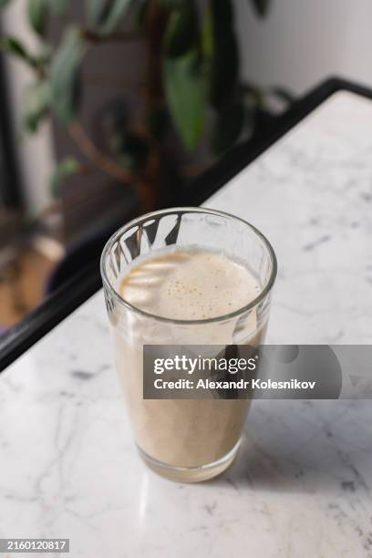 banana milkshake smoothie with oatmeal and nuts in glass on marble table - harina de avena fotografías e imágenes de stock