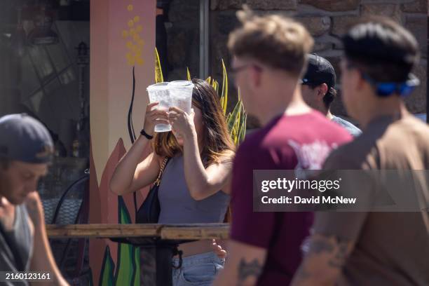 Woman holds iced drinks against her forehead as the temperature reaches 119 degrees on July 5, 2024 in Palm Springs, California. The official...