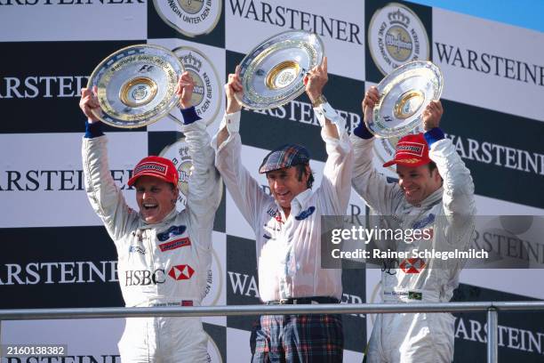 Winner Johnny Herbert, Jackie Stewart and Rubens Barrichello celebrate on the podium with their trophies during the European GP at Nürburgring on...