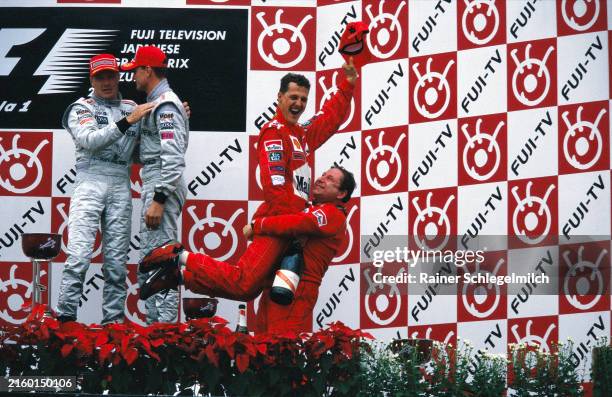 Ferrari team manager Jean Todt lifts Michael Schumacher, Ferrari, 1st position, in the air as they celebrate on the podium. Mika Häkkinen, 2nd...