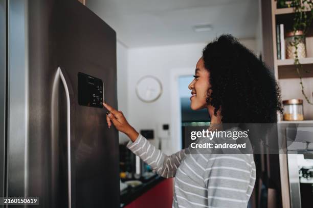 woman using smart refrigerator checking information - refrigerator stock pictures, royalty-free photos & images