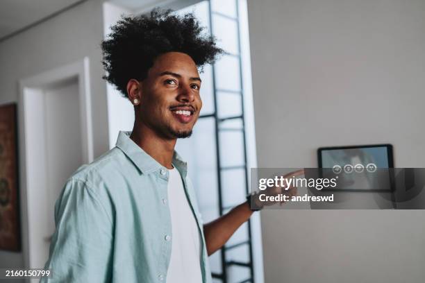 man adjusting a smart home system using a digital tablet ai - touching wall stock pictures, royalty-free photos & images