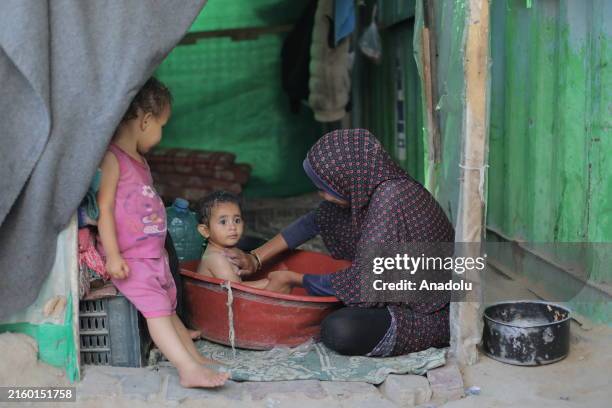 Palestinian woman giving her child a bath, in the city of Deir al-Balah, Gaza on July 2, 2024. Palestinians in the city use primitive methods to...