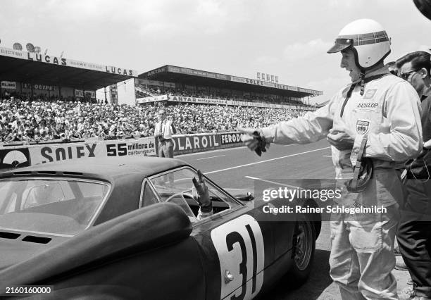Jackie Stewart gives the thumbs up to teammate Graham Hill who replies with a two finger salute, during a pitstop for the Owen Racing Organisation...