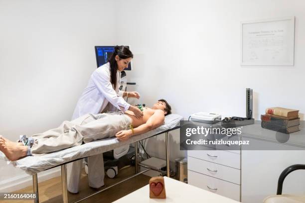 kardiologe, der ein elektrokardiogramm an einem jugendlichen patienten durchführt - echokardiogramm stock-fotos und bilder