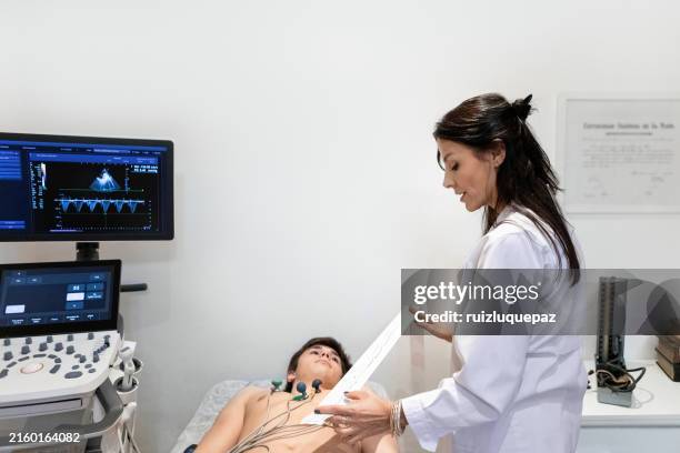cardiologist performing an electrocardiogram on a teenage patient - cardiomyopathy stock pictures, royalty-free photos & images