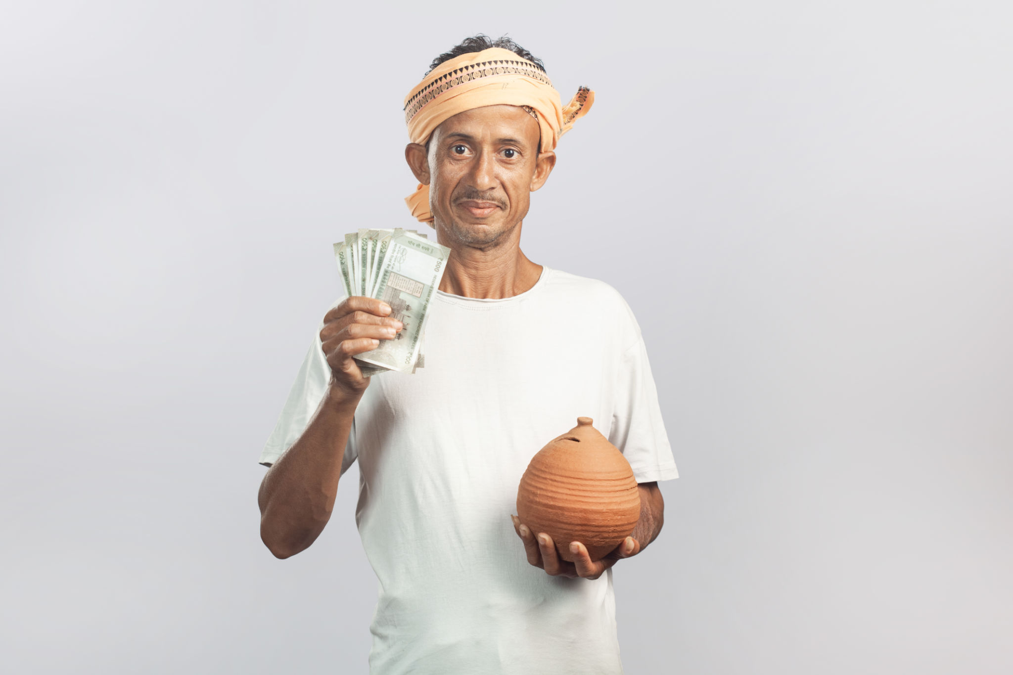 with a smiling face indian senior farmer holding a piggy bank and showing indian paper currency or rupees with a smiling face indian senior farmer holding a piggy bank and showing indian paper currency or rupees