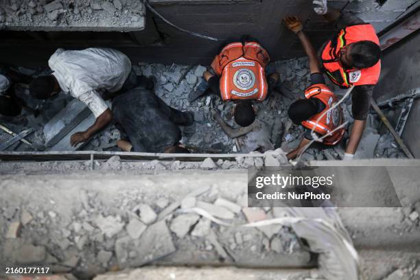 Palestinian civil defense staff are bringing out the body of a man after he was pulled out from under the rubble of a destroyed house after an...