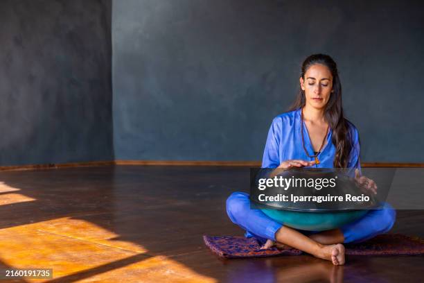 woman playing hand pan drum alone in a room - music therapy stock pictures, royalty-free photos & images