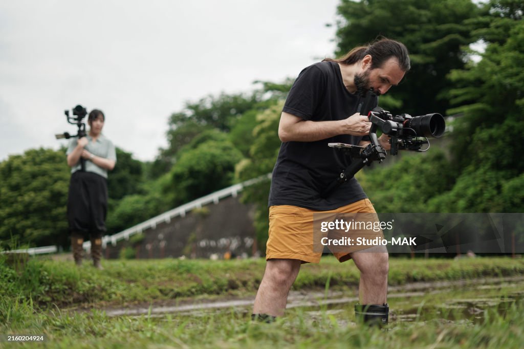 Zwei Fotografen Videofilmer bei der Aufnahme professioneller Videos in einem traditionellen japanischen Reisfeld