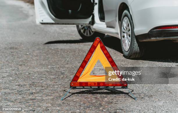 triangle de signalisation rouge chantant sur une route. voiture en panne en attente d’assistance technique en arrière-plan - accident de transport photos et images de collection
