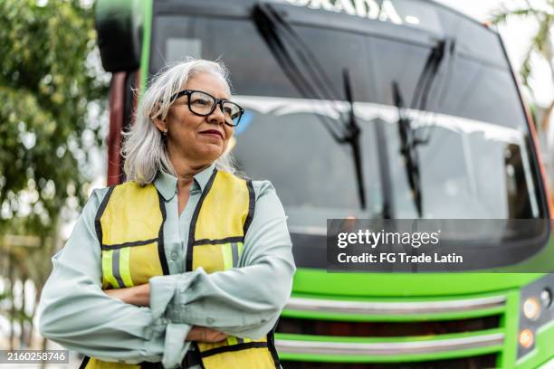 femme conductrice de bus âgée contemplant à côté d’un bus - retraités qui travaillent photos et images de collection