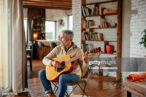 senior man playing guitar in living room - guitar stock pictures, royalty-free photos & images