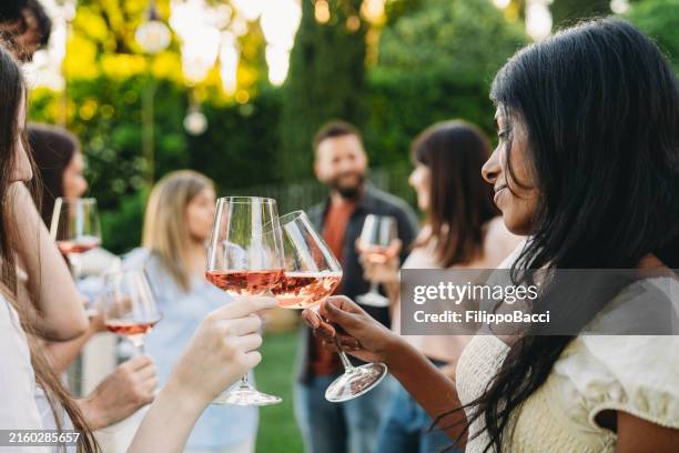 grupo de amigos haciendo un brindis con copas de vino rosado en la fiesta en el jardín - vino rosado fotografías e imágenes de stock