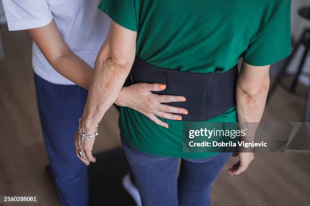 woman wearing back pain support belt - orthopedic belts stock pictures, royalty-free photos & images