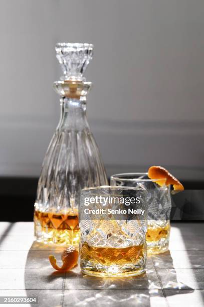 glass with bottle whiskey on a light background at noon with highlights - brandy stock pictures, royalty-free photos & images