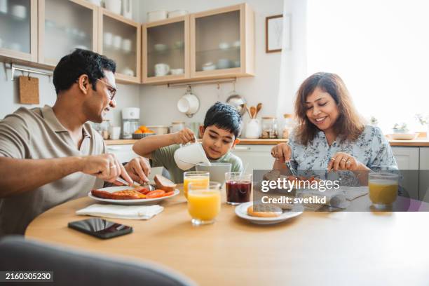 family at home starting their day in the kitchen - povo indiano imagens e fotografias de stock