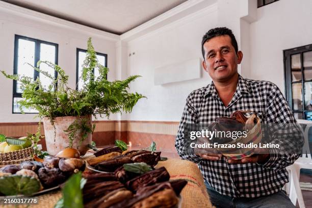 retrato de un vendedor maduro sosteniendo un tamal de maíz en una tienda de productos locales colombianos - tamal de maíz fotografías e imágenes de stock